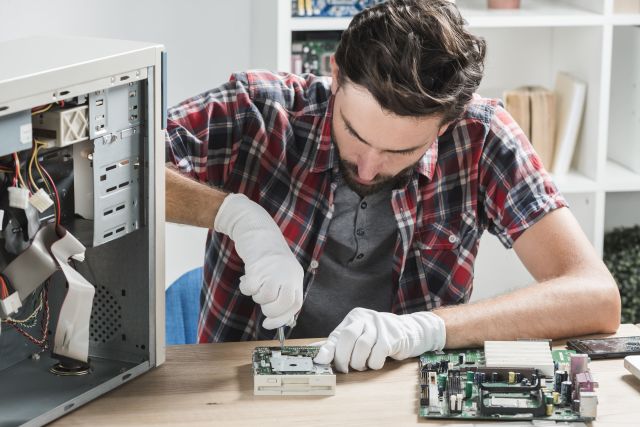 young-male-technician-wearing-gloves-fixing-computer-motherboard-with-screwdriver.jpg